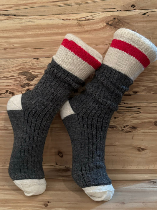 Bas en Alpaga du Travailleur Côtelé gris foncé avec talon et orteils blancs, bande rouge au mollet, posés sur un fond en bois rustique.