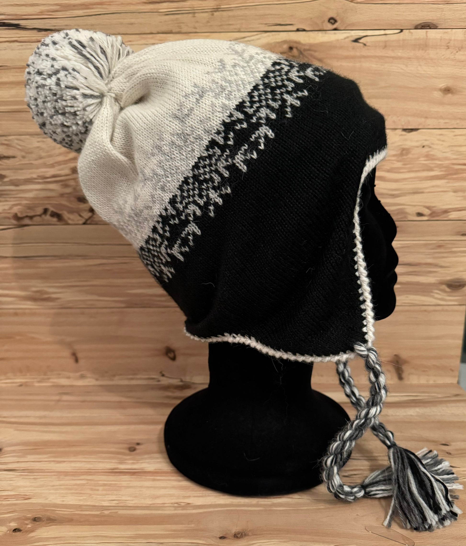 Tuque andine en alpaga noire et naturelle avec motifs traditionnels, pompon et oreillettes, idéale pour l’hiver et les activités en plein air.